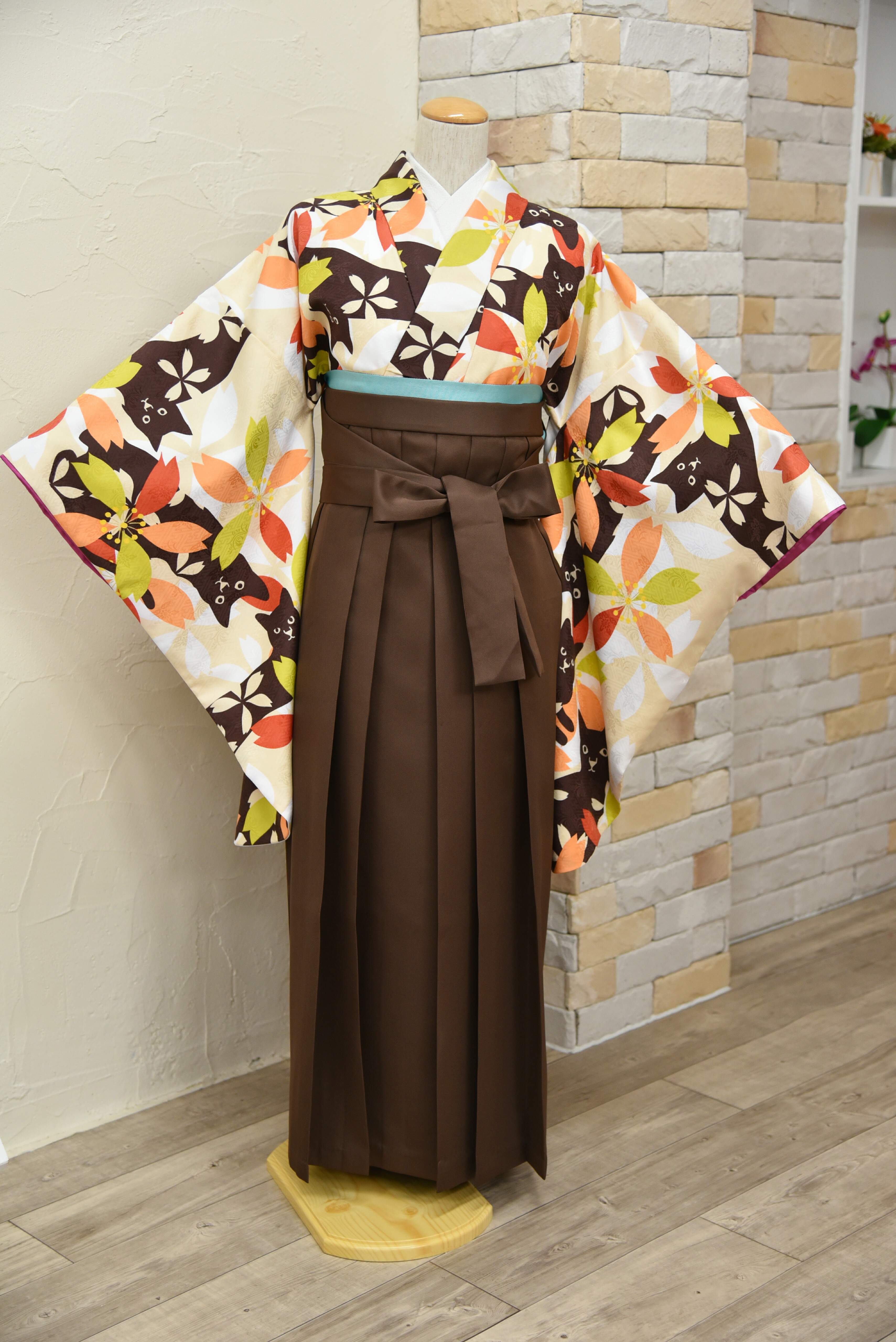 ベージュ地に桜と猫の卒業式用着物。袴は焦げ茶、帯は水色のコーディネート