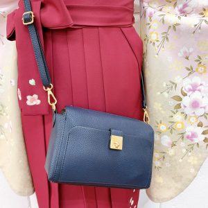 淡いベージュにピンクの桜ぼかし卒業式着物に赤色の刺繍入り袴。紺色の鞄のアップ
