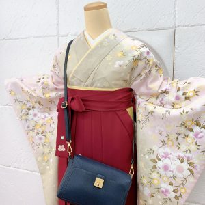 淡いベージュにピンクの桜ぼかしkimonoに赤色の刺繍入り袴。鞄は紺色