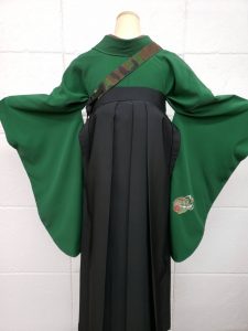 緑地に花丸刺繍だけの無地着物に黒に薔薇刺繍の袴の後ろ姿。鞄は迷彩柄のボディバッグ