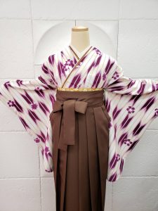 クリーム×紫の矢絣柄着物に茶色の袴。鞄は白黒のリュックサック