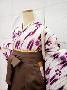 クリーム×紫の矢絣柄着物に茶色の袴。鞄は白黒のリュックサック