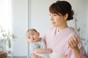 淡いピンク色のkimonoを着てヘアセット・メイクアップしたお母さん。赤ちゃんを抱っこしているお宮参りの写真