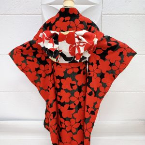 黒地に赤の桜柄の振袖の後ろ姿。帯や半襟、帯揚げ帯締め重ね衿も全て赤白黒で統一されている