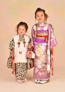 三歳七歳の姉妹で撮った和装写真。姉はjill stuart風の紫地に菊と牡丹の四つ身に、妹の着物とお揃いっぽい黒白に小さな桜の帯を着付ている。ブランド衣裳のコレクション写真のような一枚