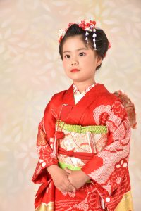 スタッフの関係者からキモノガールモデルを引き受ける事になった７才の一般家庭の女子。朱色の古典柄に京都の舞妓のような日本髪とメイクを施されてた姿は金魚が人になったよう