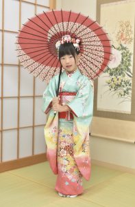 絹ならではの美しいグラデーションが楽しめる現在では希少な七歳用四つ身を着た女の子。髪にも いっぱい 花細工のヘアアクセサリーを付けている。まるで京都で見かける舞妓さん