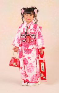 白に多彩なピンクだけでイギリスの花づくしの庭 園のようなmatsuda seikoレンタル7 53フルセットを当店でお召しいただき満足気な笑顔を浮かべるロングヘアーのお子さま。八 掛 には水玉生地、衿にはフリルのこだわり抜いた特別品質