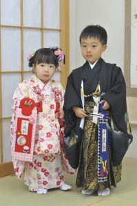 男の子は格好いい黒のhao riに珍しい個性的な袴。扇子と千歳飴を握っている。姉妹である三歳の女の子は白系クリームに赤とピンクの小紋風の可愛らしい被布。神社へのお参りもOKな三泊四日の七五 三レンタル