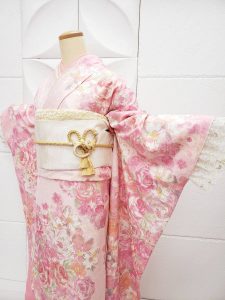 レディース服で有名なLIZLISAブランドのピンクの薔薇柄振袖。袋帯は白無垢用の白。袖を広げた正面から撮影されたマネキン写真（桃パフェをイメージしてコーディネート）