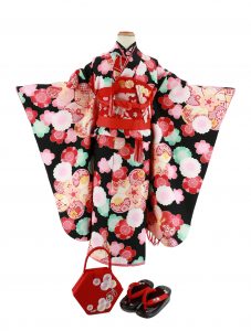 元気いっぱいの黒地に水色、ピンク・赤の桜に梅花の縁起柄が生かされた乙 葉 の七五三を祝うレンタル7 歳着物。特典でセットの刺繍入り草履・バッグや小物、小道具もお送りしています