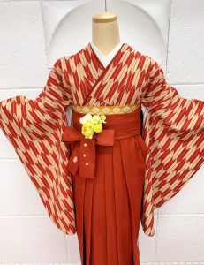 エンジとベージュの矢絣にオレンジベージュの刺繍入り袴のワントーンコーデ。卒業式では王道の古典柄で人気が高い