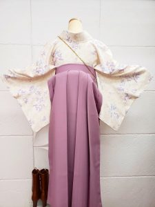 クリームにピンクと紫の花と小鳥柄小紋と薄紫色の袴の組み合わせ。卒業式袴でも淡色コーデらしいおしゃれさと女性らしさがある（後ろから撮影されたphoto）