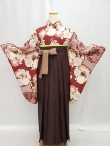 赤茶に八重桜と蝶の花の丸が描かれた絞り風二尺袖。袴は焦げ茶で内側と紐がベージュ。同じトーンでまとまったレトロモダンで落ち着いた卒業式のフルセット