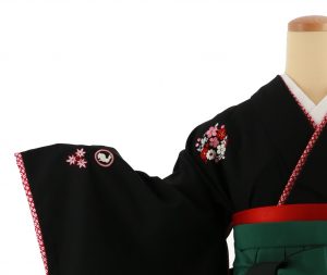 黒の無地着物（華紋の刺繍入り）に赤の反幅帯、緑から黒のグラデーション袴（白い桜の刺繍入り）の宝塚卒業式セット。ネットから宅配レンタル可能（華紋と八掛、重ね衿がよく分かる撮影写真）