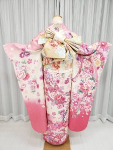 サンリオの双子キャラクター「ララ」のイメージコーデ。白とピンクの成人式振袖に水色の帯揚げや重ね衿でかわいらしく着付けている（後ろ姿）