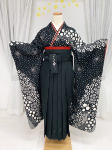 黒地の総絞り振袖にブラックの刺繍入り袴と赤の重ね衿と帯を差し色にしているコーデ
