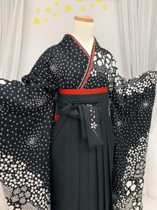 黒地の総絞り振袖にブラックの刺繍入り袴と赤の重ね衿と帯を差し色にしているコーデ