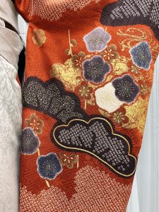 ブラウンに焦げ茶や金で松と梅、流水文様が描かれた総絞り振袖にグレーの袴を着付けた卒業式袴のコーデ写真。生地のアップ