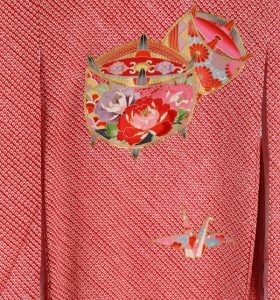 赤い総絞り地の伝統的なアンティークの女の子用産着。独楽と折り鶴の刺繍入り